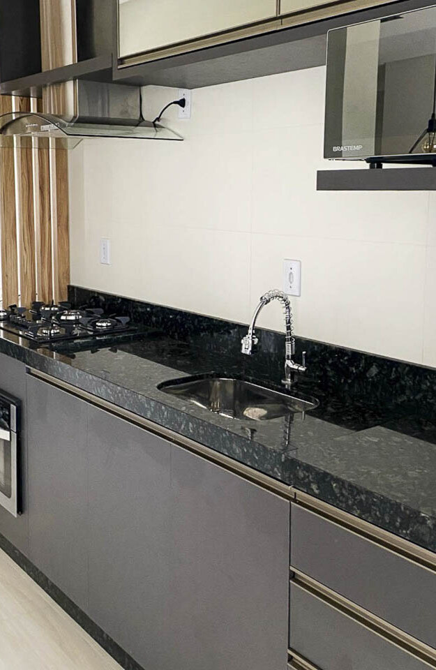 Detalhe da cozinha com forno embutido, coifa e cooktop