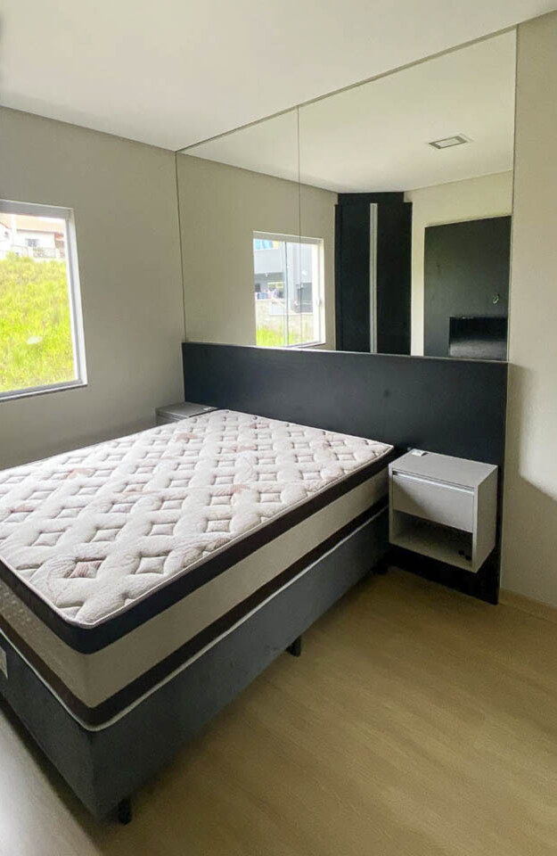 Dormitório mobiliado com espelho e cama